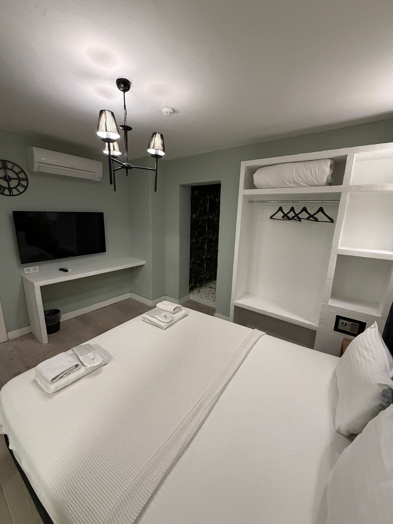 A hotel room with a large bed, a TV, a desk, and a wardrobe.