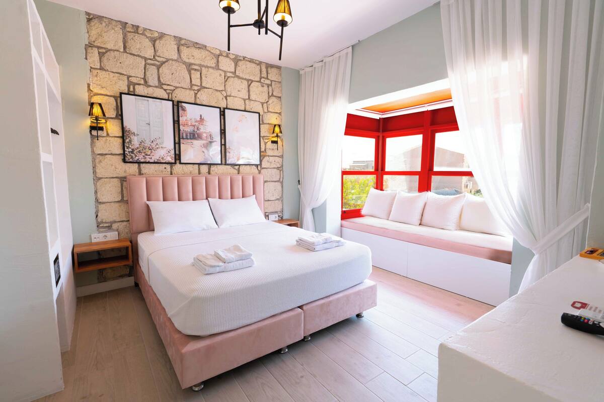 Ein Schlafzimmer mit Steinswand, einem Bett mit Kopfteil, einer Couch und einem Fenster mit Vorhängen.