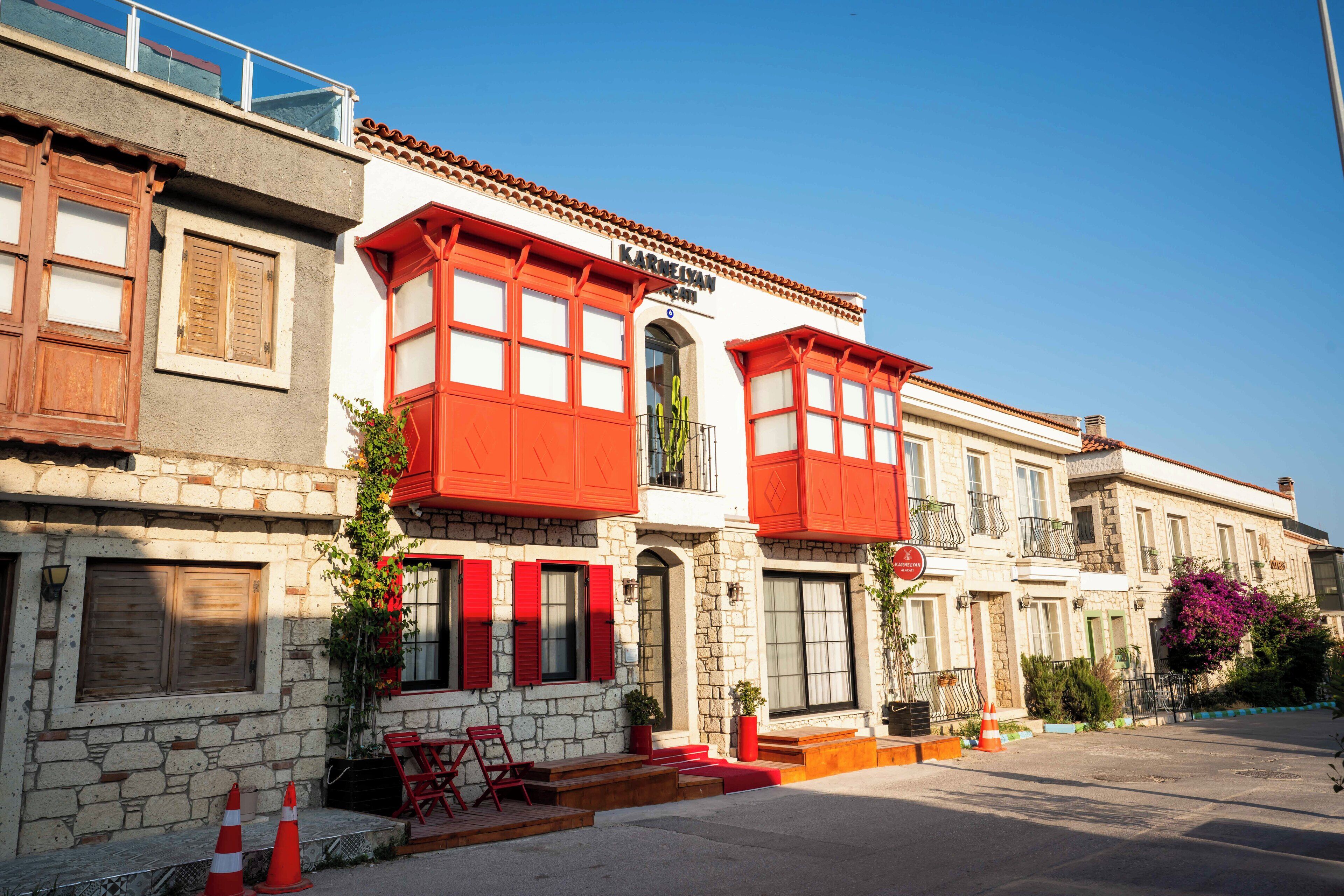 Un bâtiment doté d’une façade en pierre, de volets rouges et d’un balcon.