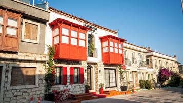 Un bâtiment doté d’une façade en pierre, de volets rouges et d’un balcon.