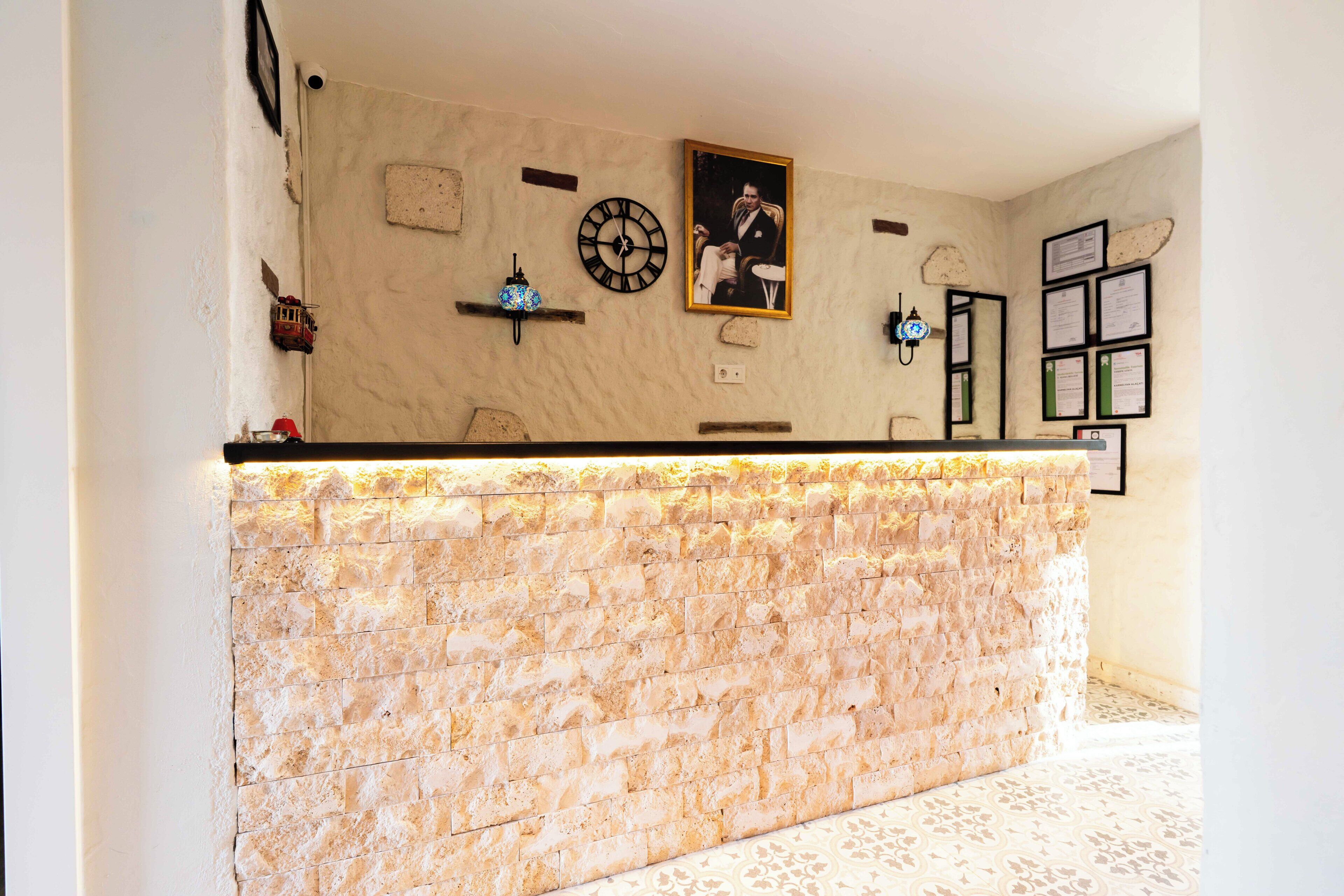 A reception area with a stone counter, a clock, framed certificates, and a small shelf with decorative items.