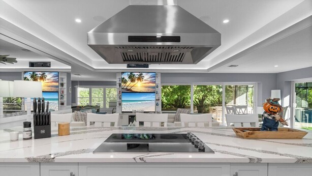 Een moderne keuken met een groot eiland, witte kasten en een roestvrijstalen afzuigkap.