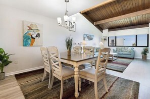 Un comedor con mesa y sillas de madera, una araña y obras de arte en las paredes.