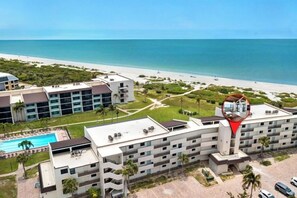 Un hotel con piscina, vistas a la playa y zona de estacionamiento.