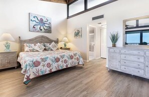 Un dormitorio con cama, mesitas de noche, cómoda y obras de arte en las paredes.