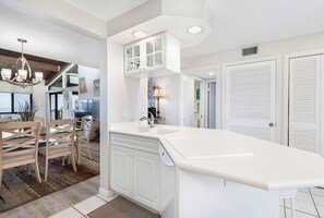 Een moderne keuken met witte kasten, een groot eiland en een eetgedeelte met houten stoelen.