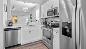 A modern kitchen with stainless steel appliances, white cabinetry, and a built-in water dispenser.