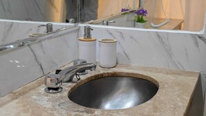 Ein Badezimmer mit Marmorwaschtisch, einem Wasserhahn und zwei Seifenspendern.