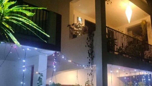 Un edificio de dos pisos con balcones, luces colgantes y plantas trepadoras.