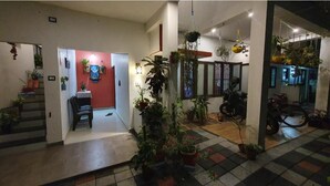 Amplia sala de estar con una pared roja decorativa, varias plantas en macetas y una motocicleta.