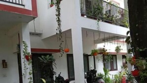 Un espacio exterior techado con plantas en macetas, piso de baldosas y una motocicleta estacionada.