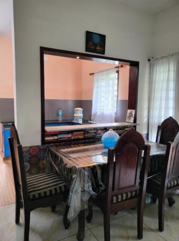 A dining area with a table and chairs, a large mirror, and a window with curtains.