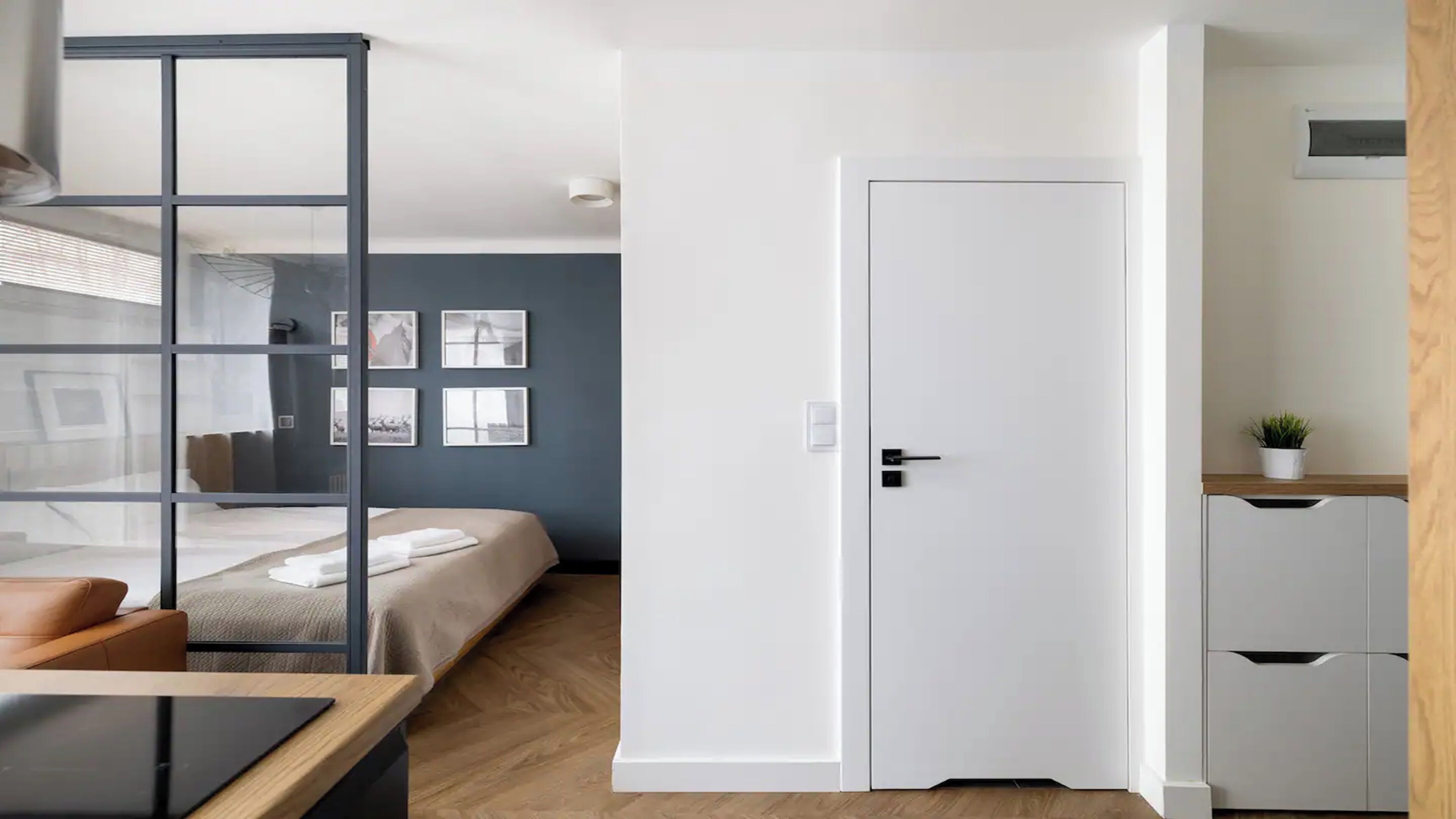 A modern hotel room with a bed, a desk, a wardrobe, and a door.