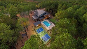 Ein großes Haus, umgeben von dichtem Wald, mit Schwimmbad und Tennisplätzen.