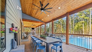 Eine überdachte Terrass mit Pool, Holzboden und blauen Stühlen.