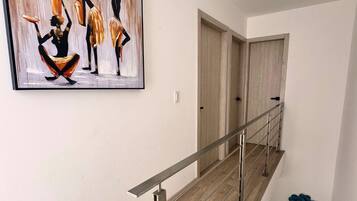 A modern interior with a wooden staircase, a minimalist painting, and a blue decorative element on the wall.