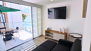 A modern living room with a black sofa, a TV mounted on the wall, and a dining area with a table and chairs. - Chipipe House, Salinas (Salinas)