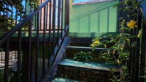 Una escalera que lleva a un edificio con fachada verde y una ventana con persianas horizontales.