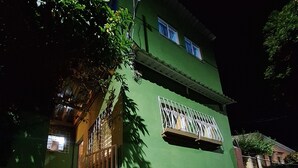 Un edificio verde con entrada protegida por una reja, una ventana visible y una escalera que conduce a la entrada.