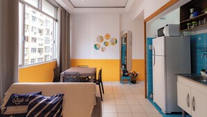 A compact living space with a dining area, kitchenette, and a view of a building outside.