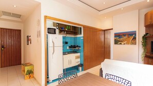 A compact kitchen with a microwave, stove, and sink, adjacent to a dining area with a table and chairs.