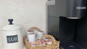 Una encimera de cocina con un tarro de azúcar, una cesta de vasos McCafé y una cafetera Keurig.