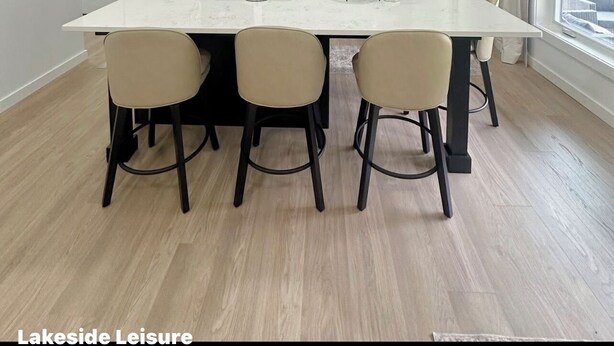 Una cocina moderna con una isla central, armarios oscuros, electrodomésticos de acero inoxidable y vistas al exterior.