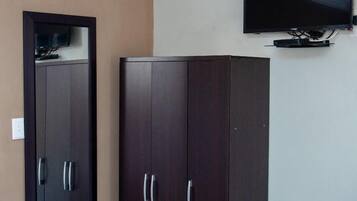 Un dormitorio con cama, armario y televisor de pared.