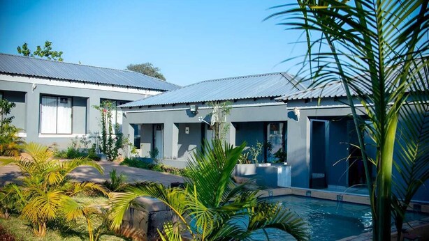 A modern building with a swimming pool surrounded by tropical plants. - LUGOGO GUESTHOUSE (Thohoyandou)