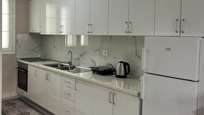 A modern kitchen with white cabinets, a built-in oven, a sink, and a refrigerator. - Elodi’s Villa (Fushkruje)