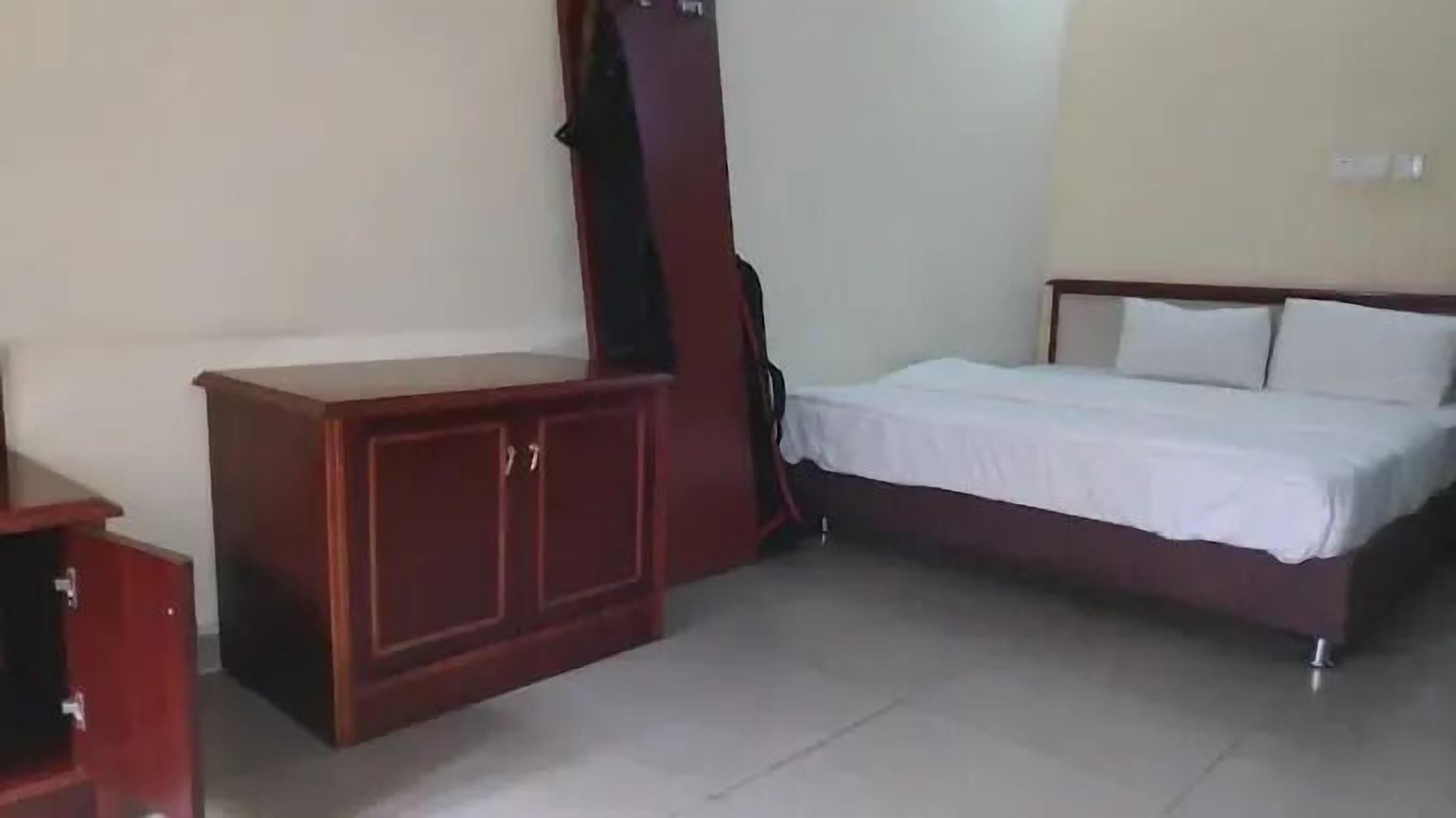 A bedroom with a bed, a wooden wardrobe, and a small table.