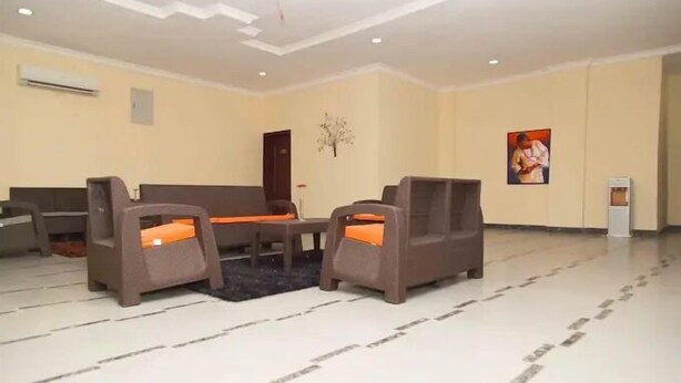 Un amplio vestíbulo con un sofá y sillones, una pequeña mesa y un adorno en la pared.