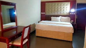 Una habitación de hotel con cama, escritorio, silla y espejo.