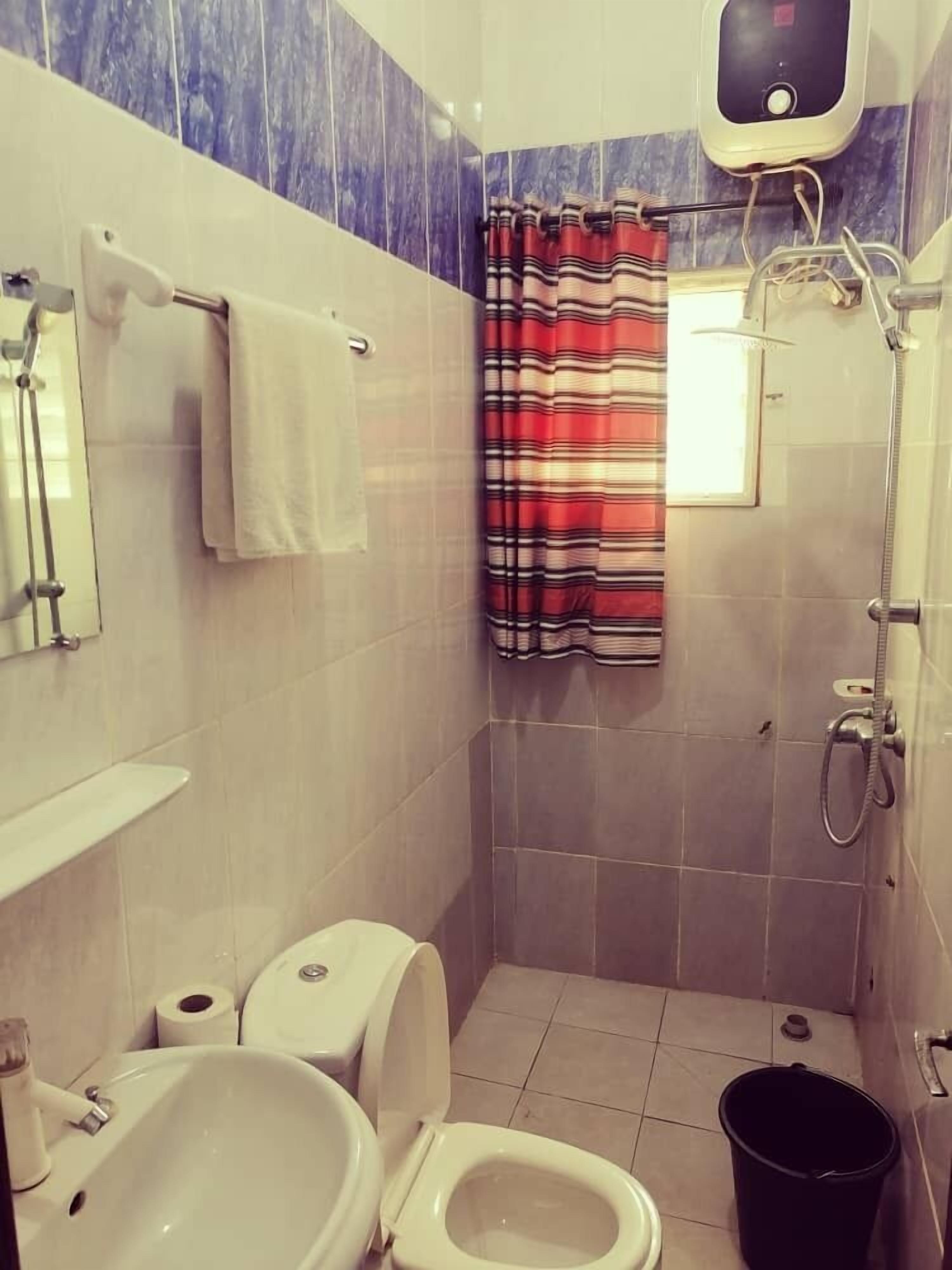 A small bathroom with a toilet, sink, shower, and a striped shower curtain.