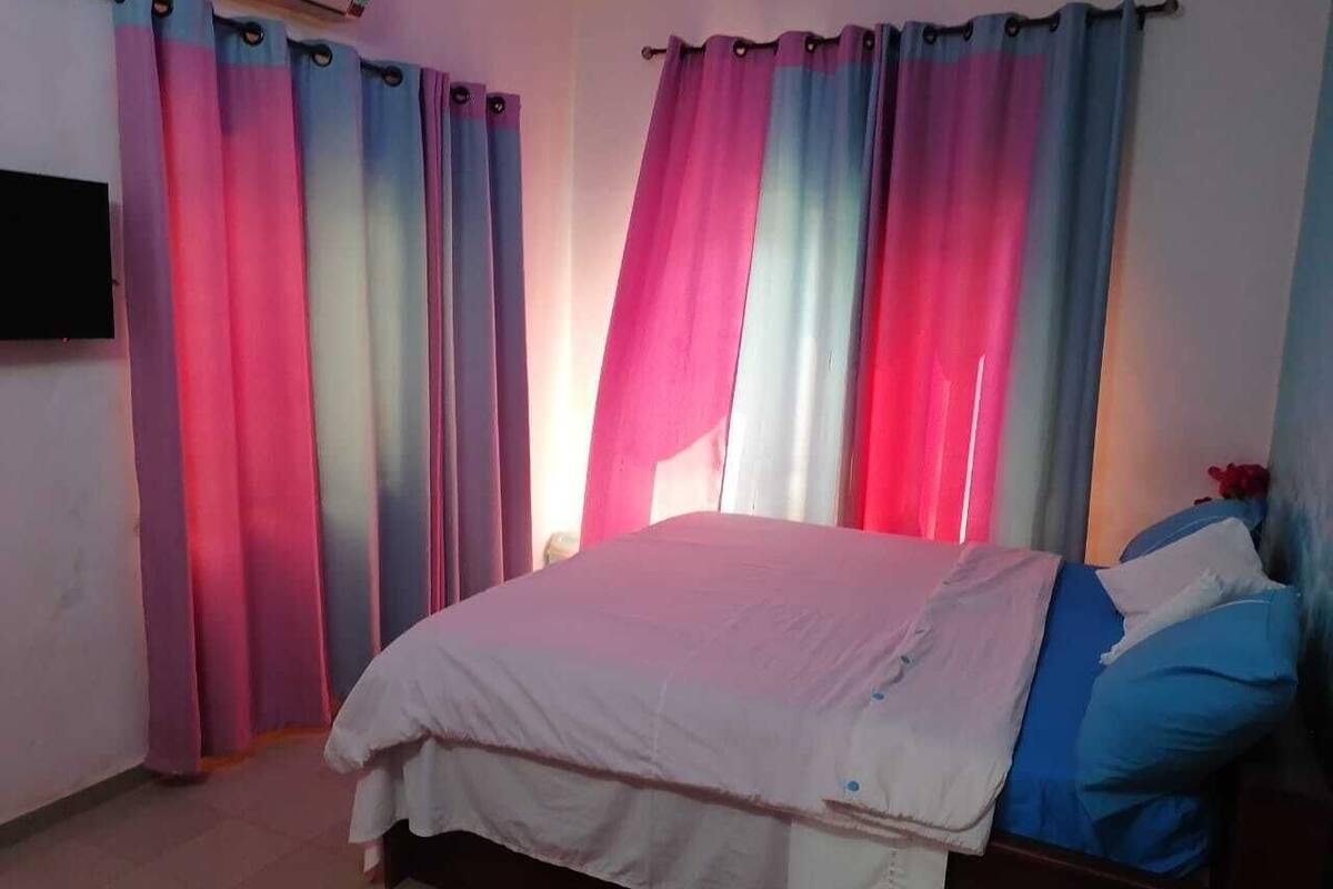 Ein Schlafzimmer mit einem Bett, Vorhängen und einem Fernseher.