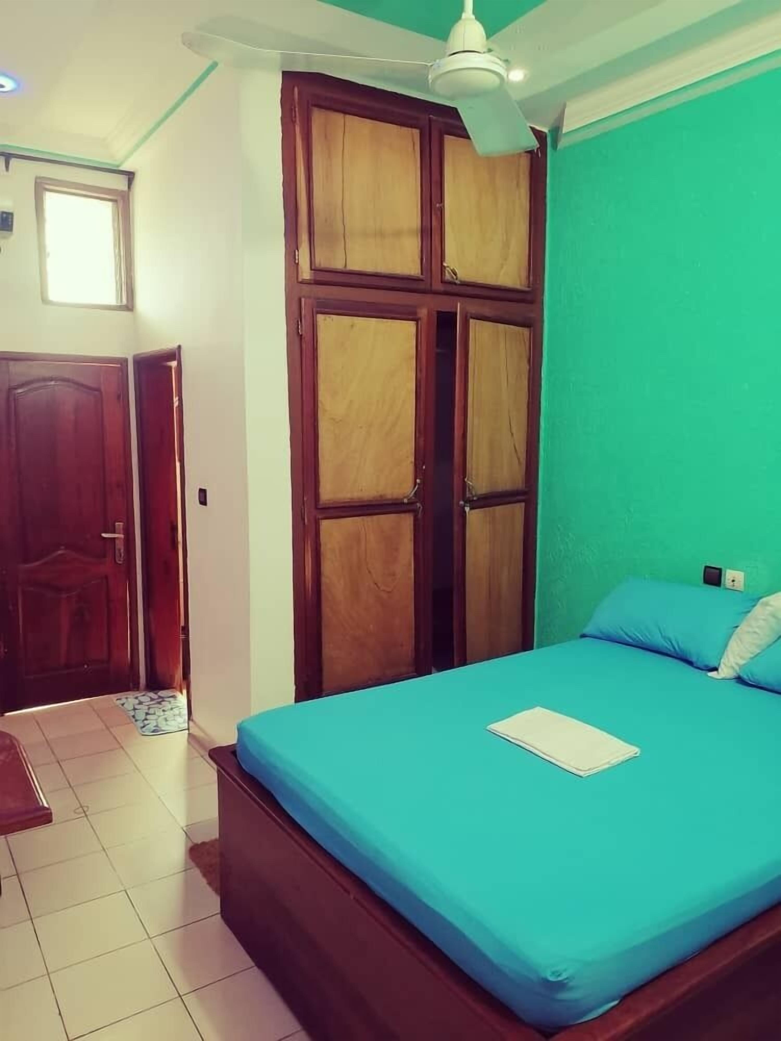 A bedroom with a bed, a ceiling fan, and a green wall.