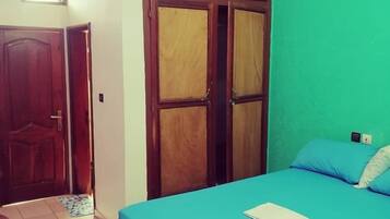A bedroom with a bed, a ceiling fan, and a green wall.