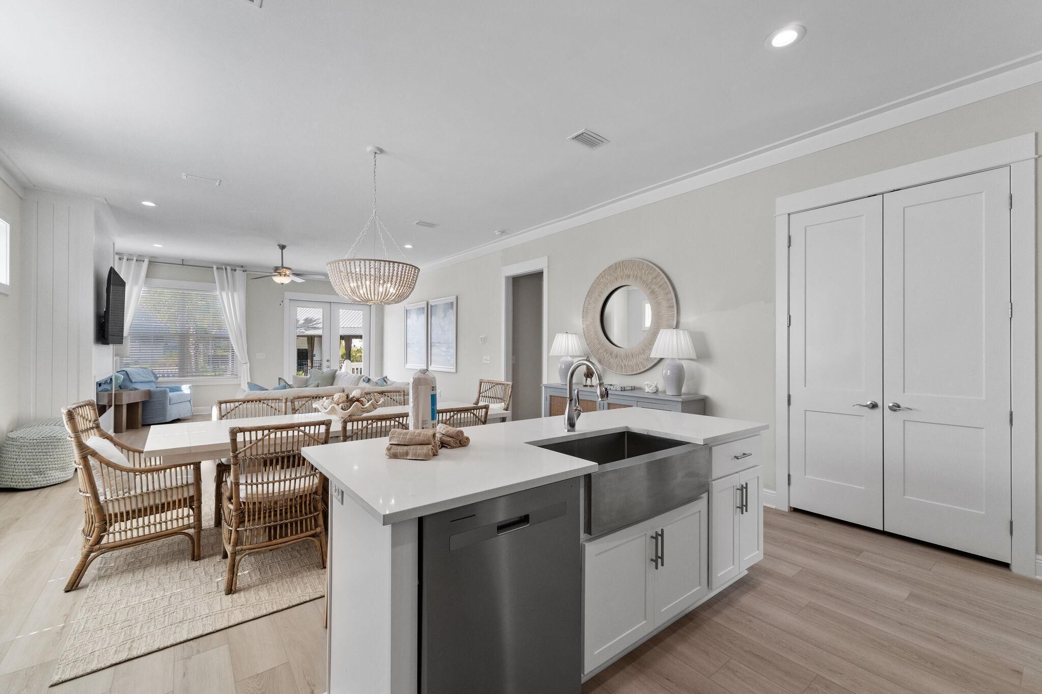 Una cocina moderna con isla central, pileta de acero inoxidable y muebles color blanco.