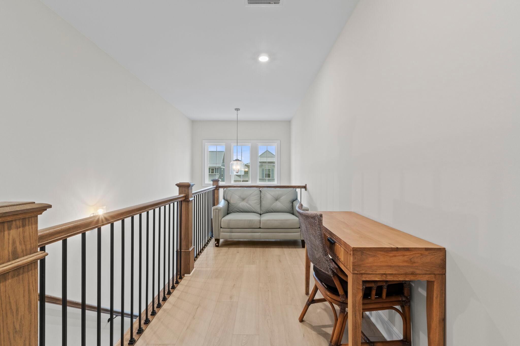 Une pièce spacieuse avec une table à manger en bois et un canapé, une balustrade en bois et une vue sur une maison, visible à travers de grandes fenêtres.