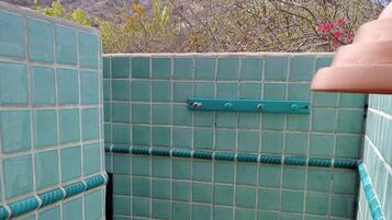 Un espacio de ducha pequeño y cerrado con azulejos verdes y un picaporte metálico.