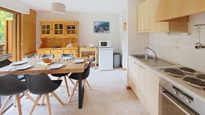Una cocina moderna con armarios de madera, un comedor con mesa dispuesta para cuatro personas y un gran ventanal.