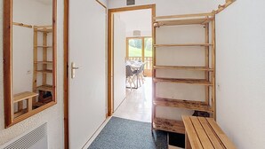 Un pasillo con un banco de madera, una puerta que da a un comedor y un espejo en la pared izquierda.