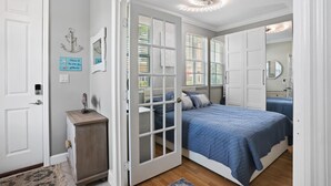 A bedroom with a bed, a wardrobe, a mirror, and a door.