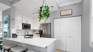 A modern kitchen with white cabinets, stainless steel appliances, and a central island with bar stools.
