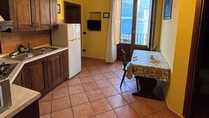 A kitchen with wooden cabinets, a white refrigerator, and a dining table with a patterned tablecloth. - Independent apartments with fully equipped kitchen in central location (Lipari)