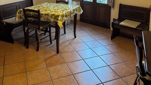 A dining area with a table set for two, a bench, and a door leading to a balcony. - Independent apartments with fully equipped kitchen in central location (Lipari)