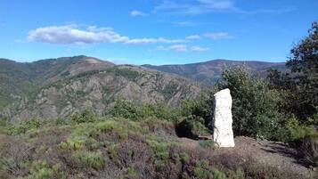 A natural landscape with a prominent white rock formation in the foreground, surrounded by greenery and hills in the background.