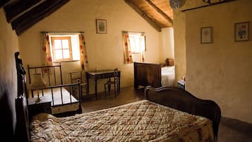 Un dormitorio con una cama, un escritorio y dos ventanas con cortinas.