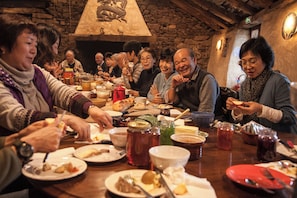 A group of people dining at a wooden table with various dishes and drinks.