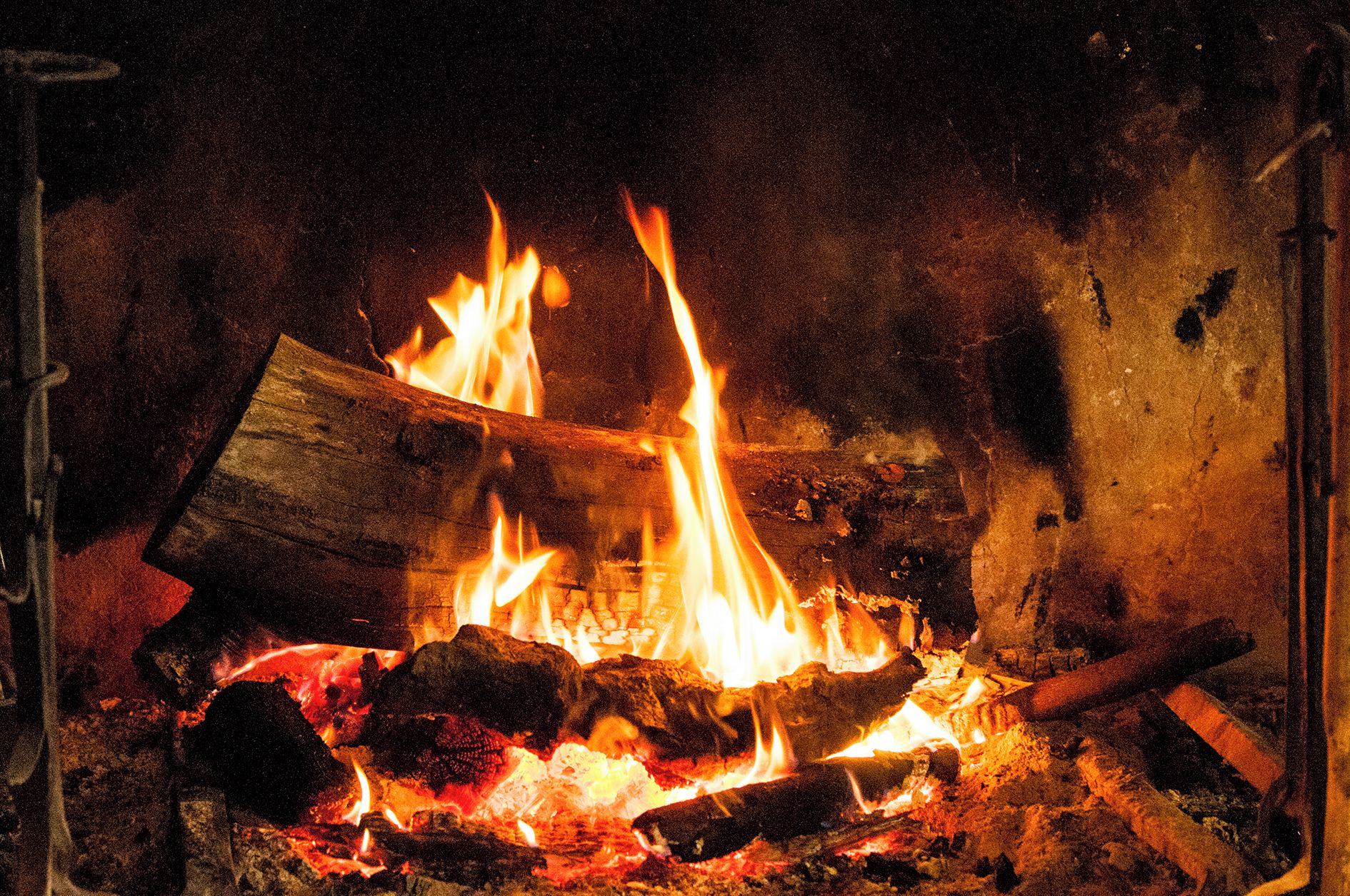 Ein Kamin mit brennenden Holzscheiten und Flammen.
